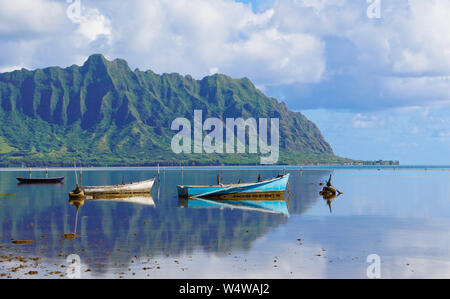 Ein perfekt noch Kaneohe Bay schafft perfekte Reflexion über die Berge und alte Boote Stockfoto