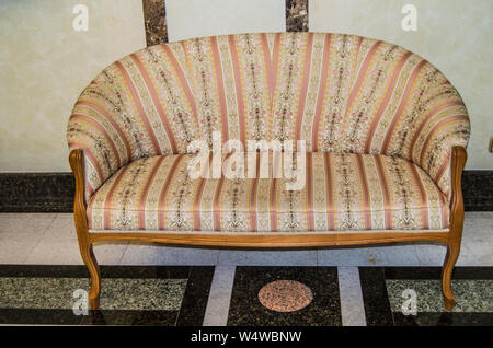 Klassisch elegante Sofa mit textile Polsterbezüge und hölzerne Beine, in Vintage Retro Stil, Marmorboden und Wänden im Wohnzimmer eines Luxus Hotel erfolgen. Stockfoto