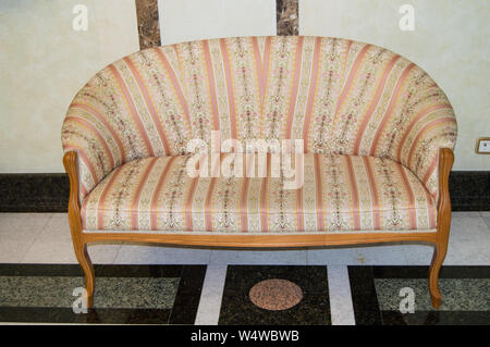 Klassisch elegante Sofa mit textile Polsterbezüge und hölzerne Beine, in Vintage Retro Stil, Marmorboden und Wänden im Wohnzimmer eines Luxus Hotel erfolgen. Stockfoto