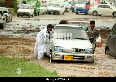 Rawalpindi, Pakistan. 25. Juli, 2019. Die Menschen drücken Sie ein Auto, da es in der Flut nach schweren Monsunregen in Rawalpindi, Pakistan, 25. Juli 2019 fest. Credit: Ahmad Kamal/Xinhua/Alamy leben Nachrichten Stockfoto