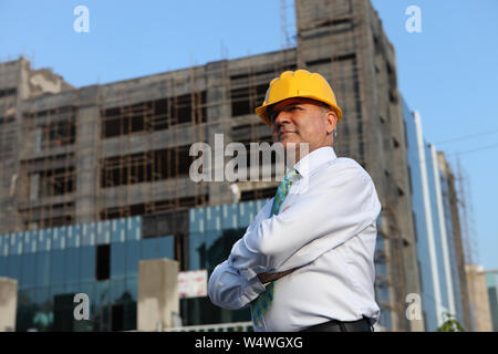 Architekt steht mit gekreuzten Armen auf der Baustelle Stockfoto