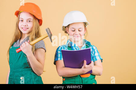 Meister Inspektor. Reparatur. glückliche Kinder. Berufliche Zukunft. Kleine Kinder im Helm mit Tablet und einem Hammer. Tag der Arbeit. 1. kleine Mädchen zusammen die Reparatur in der Werkstatt. Nach einem harten Arbeitstag müde. Stockfoto