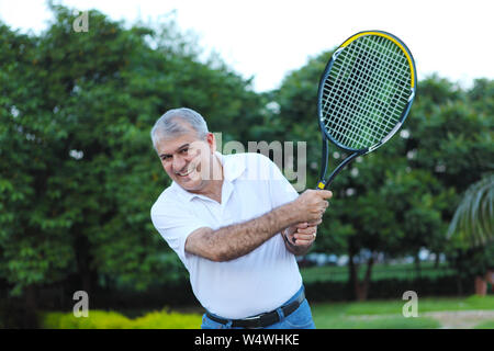 Mann spielt einen Tennisschläger und lächelt Stockfoto