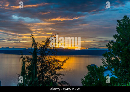Die Wolken hängen am Himmel, wie die Sonne hinter den Olympic Mountains im Staat Washington. Stockfoto