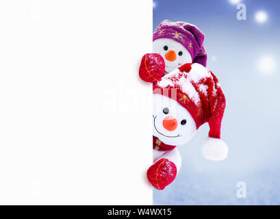 Zwei kleine Schneemänner das Mädchen und der Junge in Mützen und Schals auf Schnee im Winter. Festliche Hintergrund mit einem lustigen Schneemann. Weihnachtskarte, kopieren. Stockfoto