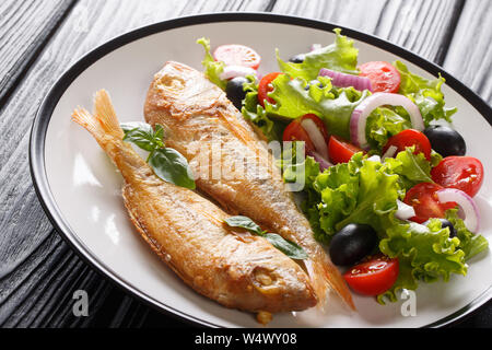 Gesunde gebackene rosa Dorado mit Zitrone und frisches Gemüse in der Nähe serviert auf einem Teller auf den Tisch. Horizontale Stockfoto