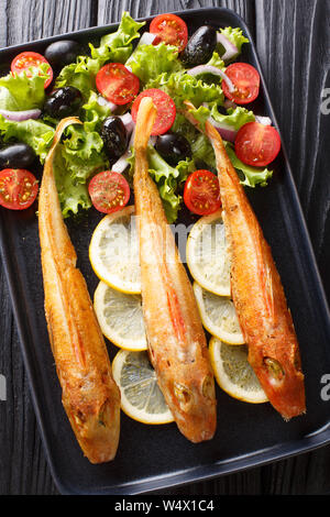 Köstliche frische gebratene Fische Knurrhahn mit frischem Gemüse und Salat Zitrone close-up auf einem Teller auf den Tisch. Vertikal oben Ansicht von oben Stockfoto
