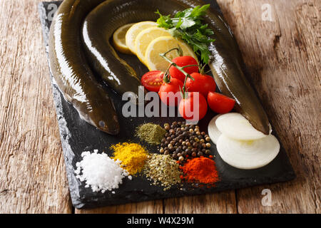 Frisch Aal mit Gewürzen, Zitronen, Tomaten und Zwiebeln close-up auf einer Schiefertafel Board auf dem Tisch erwischt. Horizontale Stockfoto