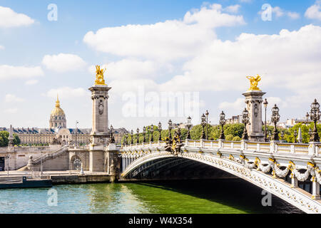Der Pont Alexandre III über die Seine in Paris, Frankreich, mit der Kuppel des Invalides im Hintergrund an einem sonnigen Sommermorgen. Stockfoto