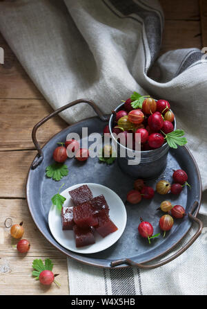 Stachelbeer Marmelade, Würfel und Stachelbeeren auf eine Dose Fach rustikalen Stil. Stockfoto