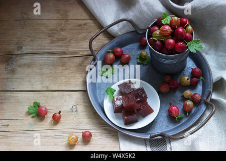 Stachelbeer Marmelade, Würfel und Stachelbeeren auf eine Dose Fach rustikalen Stil. Stockfoto