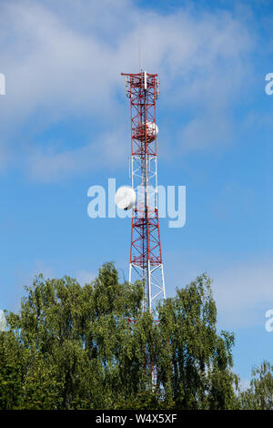 Rot-weiß Telekommunikationsturm mit der Oberseite der Grüne Baum auf blauen Himmel mit Wolken Hintergrund, Stockfoto