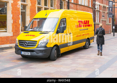 Frau zu Fuß vorbei an einer DHL-Kurier van, High Street Lieferungen, Leicester, England, Großbritannien Stockfoto