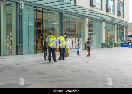Zwei Sicherheit Personal tragen hohe Sichtbarkeit jacken Leitung einer Gruppe von Menschen außerhalb der Highcross Einkaufszentrum, Leicester, England Großbritannien Stockfoto