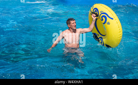 Glücklich ist der Mensch genießen Sommer Wochenende im Freizeitpark Wasserpark. Pensionierter, aber immer noch aktiven Erwachsenen in seinen Sechzigern aus dem Pool halten Stockfoto