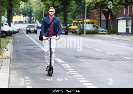 Portrait einer jungen Geschäftsmann, Elektrische Roller auf der Straße in der Stadt Stockfoto