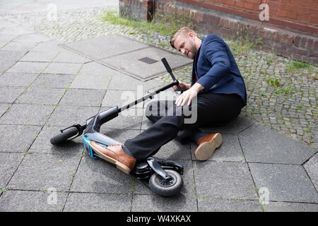 Junger Mann Unfall mit einem elektrischen scooter Auf der Straße Stockfoto