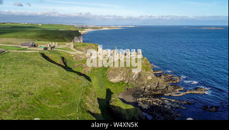 Die Ruinen der mittelalterlichen Dunluce Castle auf einem steilen Felsen in der Nähe von Folkestone. Der nördlichen Küste des County Antrim, Nordirland, Großbritannien. Luftaufnahme im Sonnenaufgang. Stockfoto