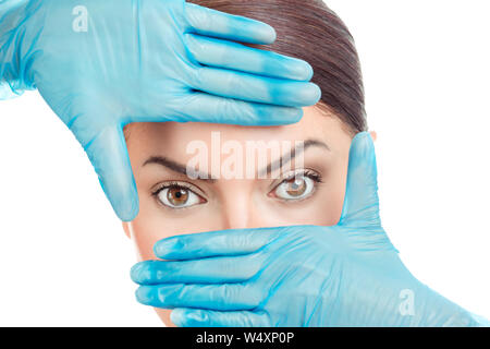 Arzt Hand in Handschuhe die Gestaltung eines Rahmens um die Augen eines Mädchens. Frau bereitet zu haben Augen Chirurgie durchgeführt, isolierten Ausschnitt auf weißem Hintergrund mit c Stockfoto