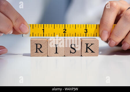 In der Nähe von eine Geschäftsfrau Hand Risikomessung Blöcke mit gelbem Maßband Stockfoto