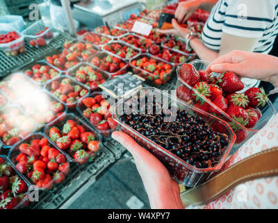 Seitenansicht des französischen Frau Shopping für frische Johannisbeeren und Erdbeeren auf Bauernmarkt - Bio Bio Lebensmittel im französischen Dörfer geerntet Stockfoto