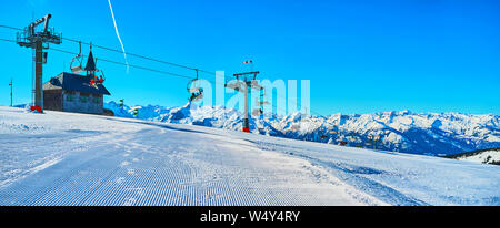 Panorama der Schmittenhohe Mountain Top mit perfekter corduroy Piste, Kapellenbahn Sessellift, kleine Elisabeth Kapelle und alpinen Bereich auf Hintergrund, Stockfoto