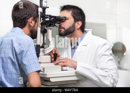 Männlicher Arzt Augenarzt überprüft das Auge Vision von gutaussehenden jungen Mann in der modernen Klinik. Arzt und Patient in der Augenheilkunde Klinik. Stockfoto