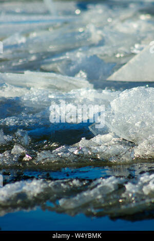 Eisbrocken schwimmend auf dem Fluss. Kristall Oberfläche auf dem Hintergrund des blauen Wassers. Driften im frühen Frühling. Schöne Eis motion Nahaufnahme. Stockfoto