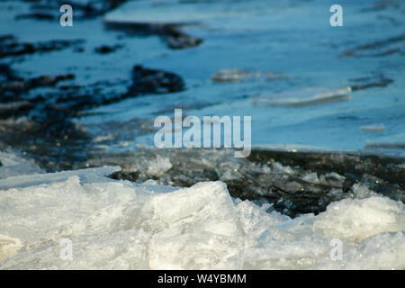 Eisbrocken schwimmend auf dem Fluss. Kristall Oberfläche auf dem Hintergrund des blauen Wassers. Driften im frühen Frühling. Schöne Eis motion Nahaufnahme. Stockfoto