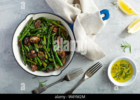 Spargel und Champignons sautierte in einer gusseisernen Pfanne mit Zitronenschale Stockfoto
