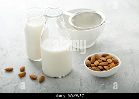 Hausgemachtes Mandel Milch in Glasflaschen mit einem Sieb Stockfoto