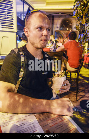 Republik nördlich Skopje, Mazedonien - 24. AUGUST 2018: Nacht in Mazedonien Platz. der Mensch isst ein Kebab spät in der Nacht. Stockfoto