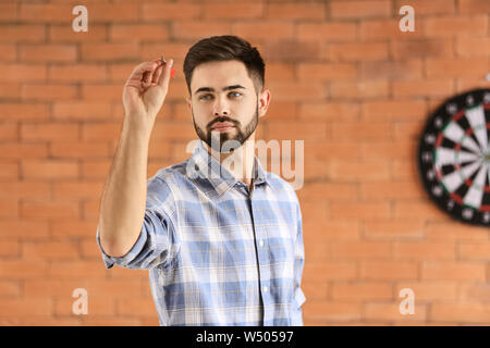 Junge Mann spielt Dart im Innenbereich Stockfoto