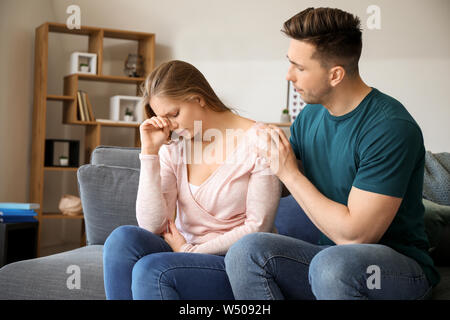 Den jungen Mann, der versucht, Frieden mit seinem beleidigten Ehefrau zu Hause Stockfoto