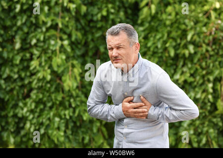 Reifer mann Leiden von Herzinfarkt im Freien Stockfoto