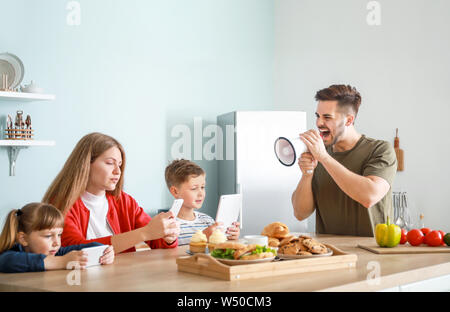 Mann mit Megaphon Schelte seiner Familie mit Neigung zu modernen Technologien zu Hause Stockfoto