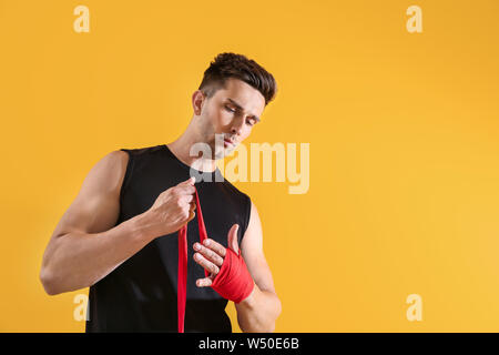 Sportlicher junger Mann Anwendung Armbänder gegen Farbe Hintergrund Stockfoto