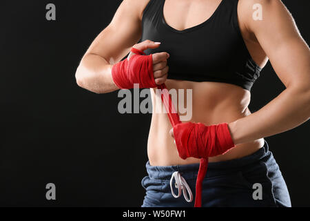 Sportliche weiblichen Boxer Anwendung Armbänder gegen den dunklen Hintergrund Stockfoto