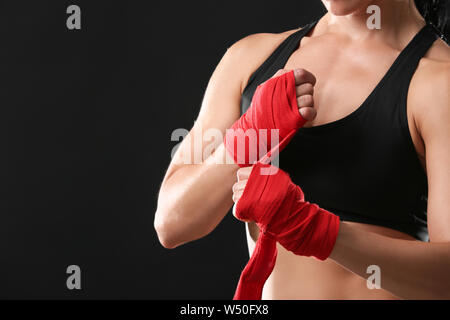 Sportliche weiblichen Boxer Anwendung Armbänder gegen den dunklen Hintergrund Stockfoto