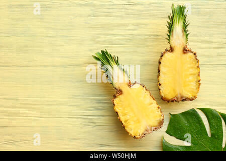 Hälften von Ananas und tropischen Blatt auf Holz- Hintergrund Stockfoto