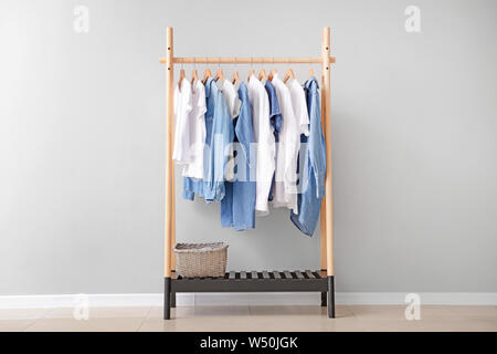 Rack mit hängenden Kleidung in der Nähe von hellen Wand Stockfoto