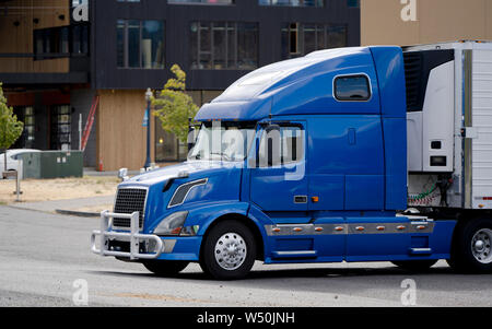 Hell Blue Bonnet Big Rig Semi Truck mit Schutzgitter guard Entladen der kommerziellen Ladung von Kühlschrank Auflieger auf der Seite der Lieferung in Stockfoto