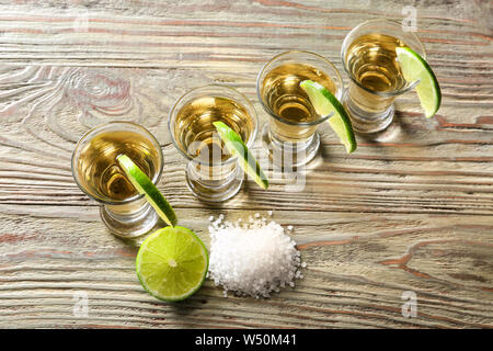 Schüsse von leckeren Tequila mit Kalk und Salz auf hölzernen Tisch Stockfoto