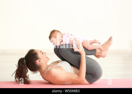 Mutter Yoga mit niedlichen kleinen Babys zu Hause Stockfoto