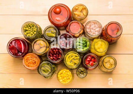 Gläser mit verschiedenen Gemüsekonserven auf hölzernen Hintergrund Stockfoto