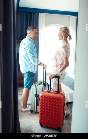 In Urlaub gehen. Lächelnd Mann und Frau ihre Reisen fällen Holding vor verlassen ihre Heimat. Stockfoto