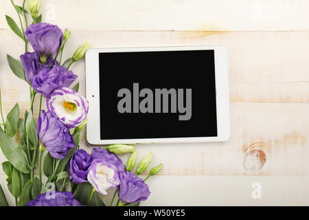 Modernen Tablet Computer mit Strauß Blumen auf weißem Holz- Hintergrund Stockfoto