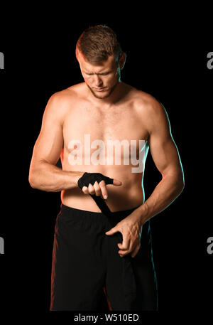 Starke männliche Boxer Anwendung Armbänder gegen den dunklen Hintergrund Stockfoto