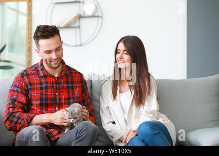 Glückliches Paar mit niedlichen Katze zu Hause ausruhen Stockfoto