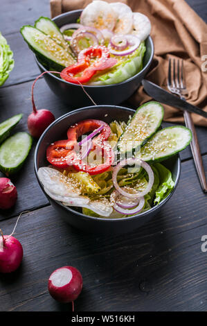 Close-up-Salat mit Radieschen, Gurken, Zwiebeln, Paprika und Sesamöl. Vertikale erschossen. Gesundes Essen. Stockfoto
